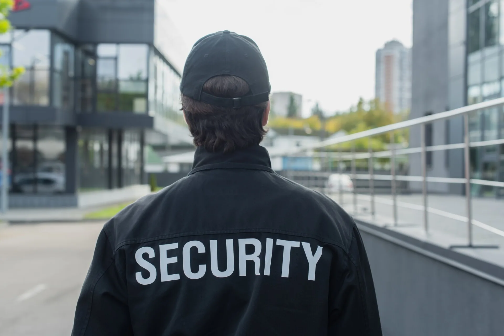 back view of guard in uniform with security lettering standing on city street